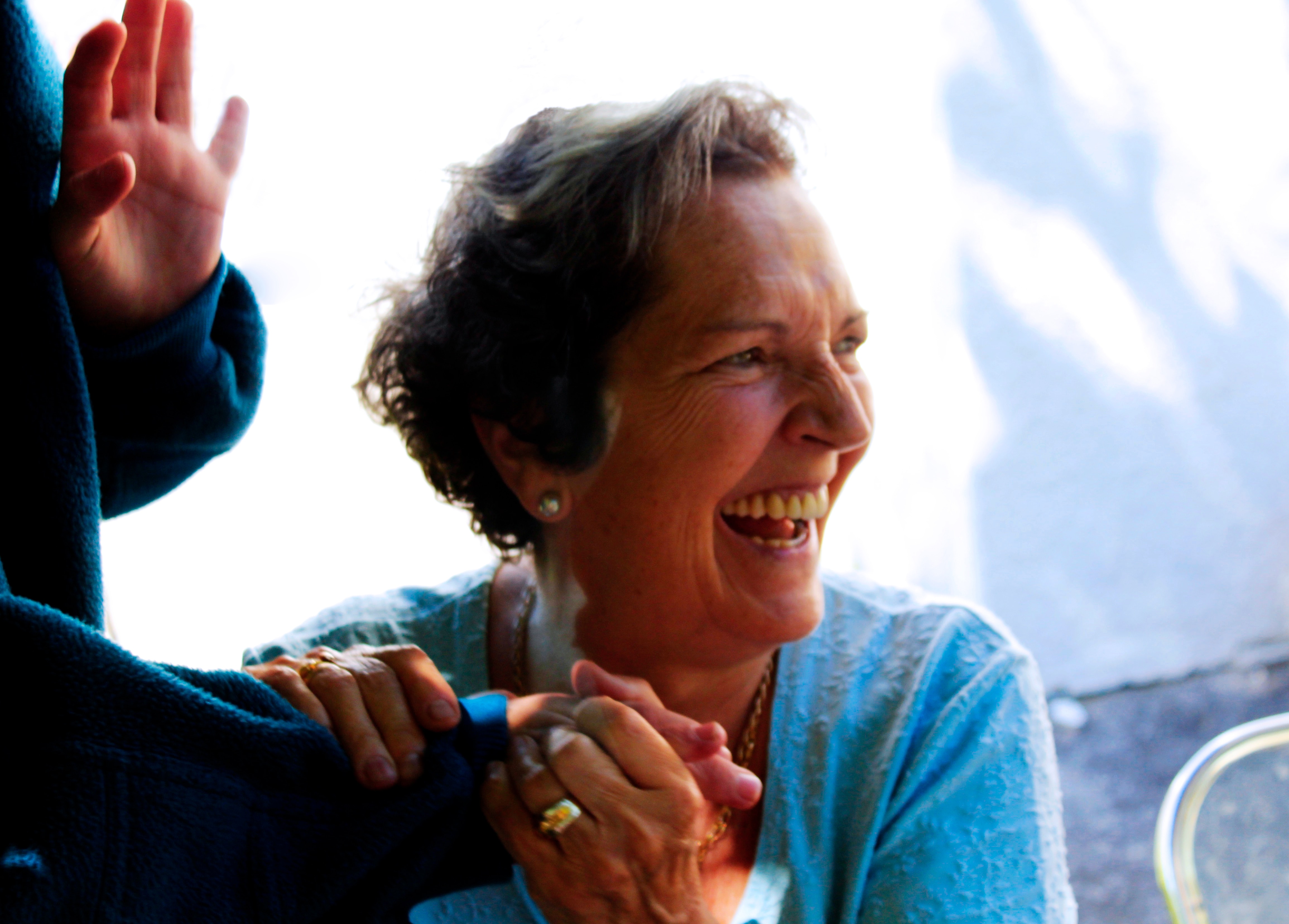 Older woman looking off into distance smiling holding someones hand