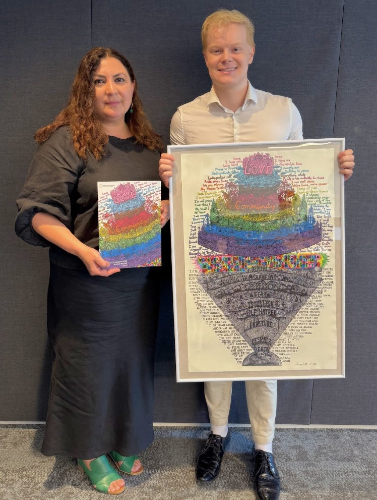 Woman holding a report standing next to a man holding a framed artwork.